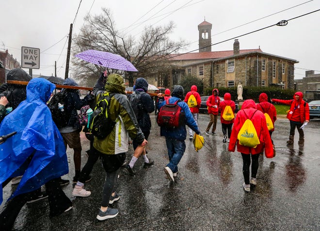Pilgrims carry a wooden cross (left) from W. 10th Street onto N. Dupont Street to St. Antony of Padua as the Catholic Diocese of Wilmington's Catholic Youth Ministry cross pilgrimage heads for the church from its starting point at St. Elizabeth, Saturday, March 23, 2024.