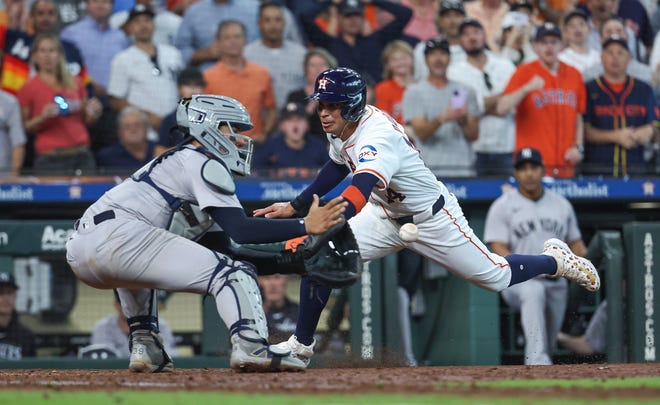 Houston Astros second baseman Mauricio Dubon attempts to score a run but is tagged out by New York Yankees catcher Jose Trevino during the ninth inning at Minute Maid Park.