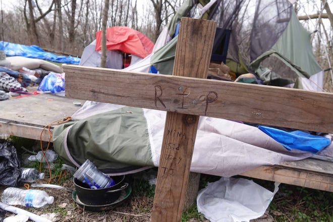 A cross with names of the four victims found dead in a tent on Tuesday afternoon in a homeless camp in Stanton was left in front of the tent on Wednesday morning.