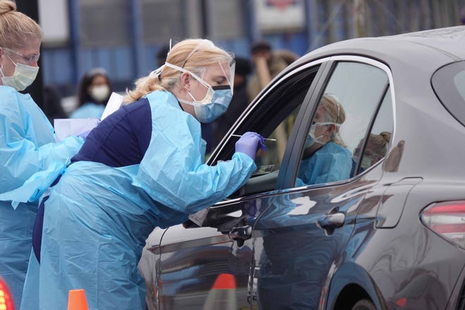 A healthcare worker with ChristianaCare takes a swab from a person in a vehicle during a drive-thru coronavirus testing setup in the parking lot of Chase Center in March. Tests were free, and patients will receive their results in two to five days.