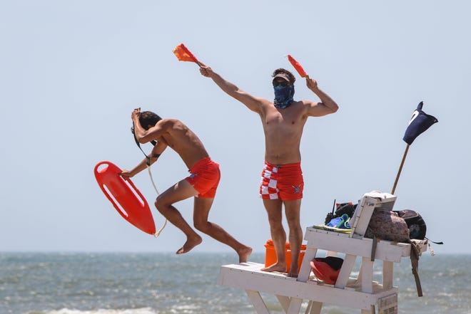 Lifeguards demonstrate a rescue on a crowded Bethany Beach on a warm breezy Wednesday, June 10. They were trained to work in teams for rescues, wearing masks and gloves when possible due to coronavirus.