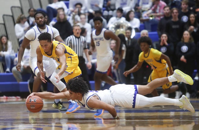 Dover's Elijah Allen dives to maintain control of the ball after slipping in front of Caesar Rodney's Syed Miles in the Senators' 93-72 win at Dover High School in January.